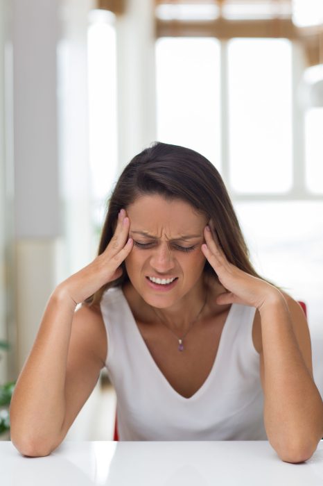 Angry young woman rubbing temples while having headache. Exhausted businesswoman trying to concentrate. Frustration concept